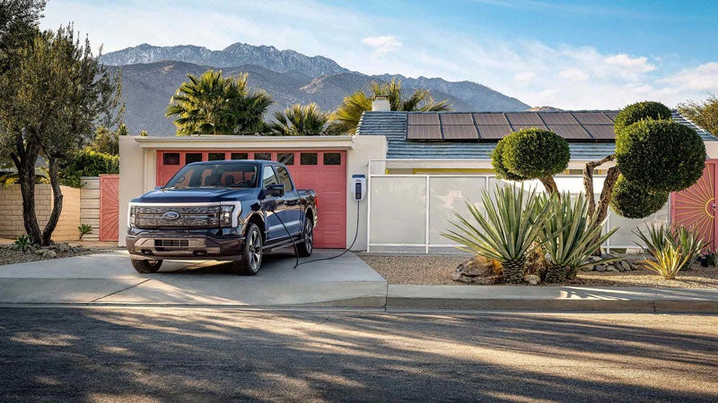 An F-150 Lightning charges in a driveway in the daytime